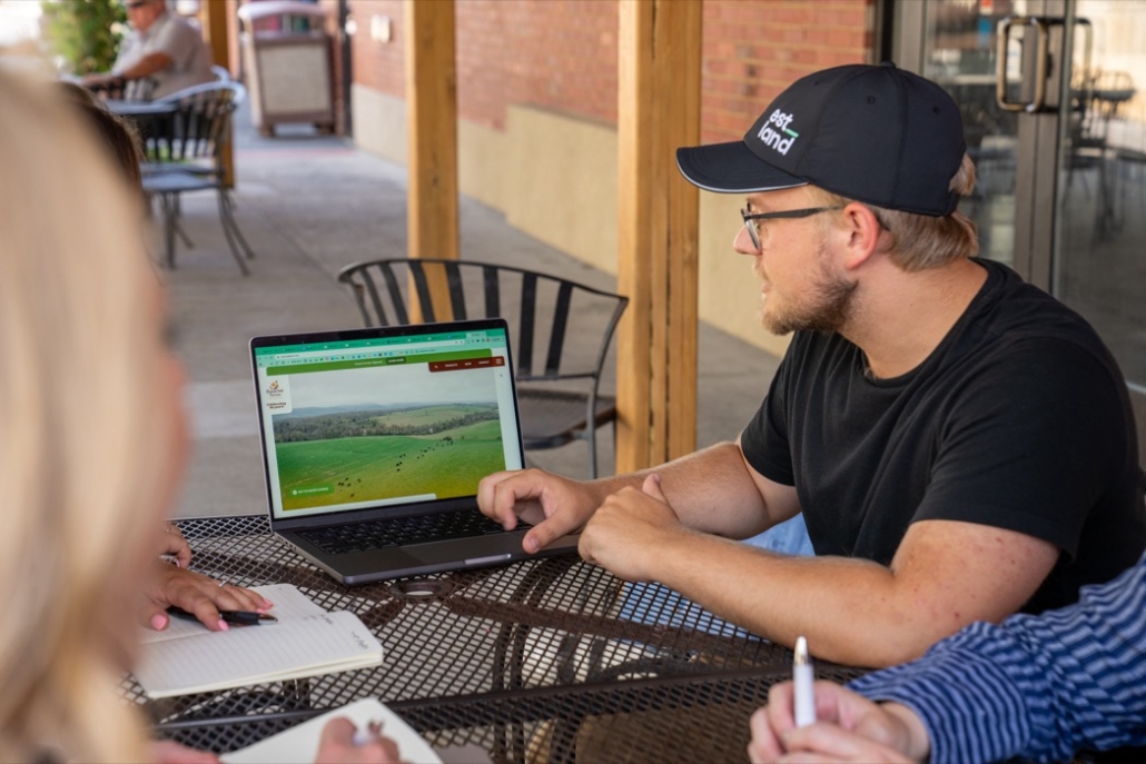 Estland employee sitting at outdoor table with laptop out working on marketing plan
