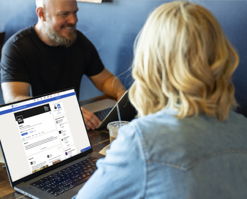 Estland team members at a table with Estland's LinkedIn page pulled up on a laptop.