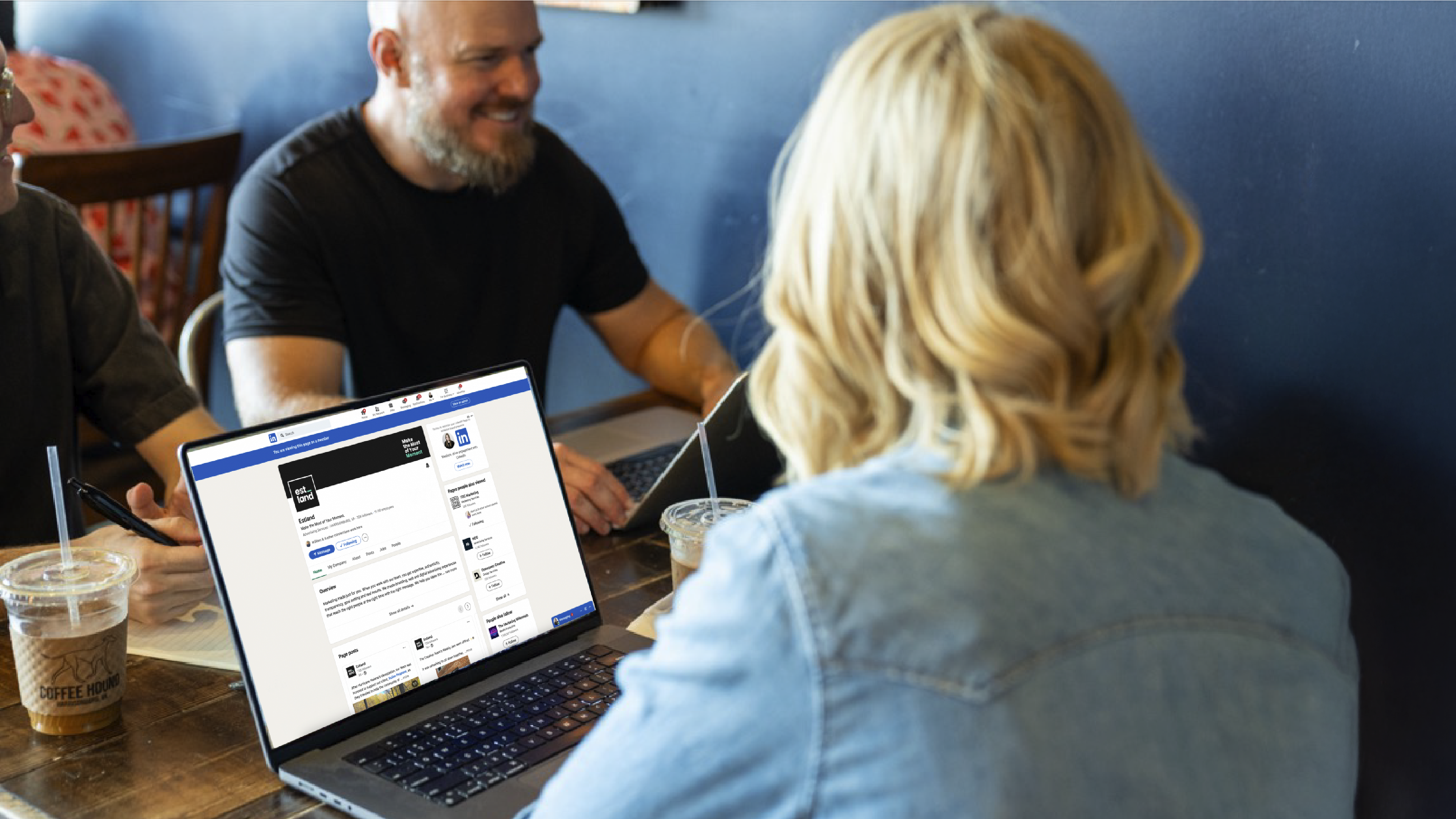 Estland team members at a table with Estland's LinkedIn page pulled up on a laptop.