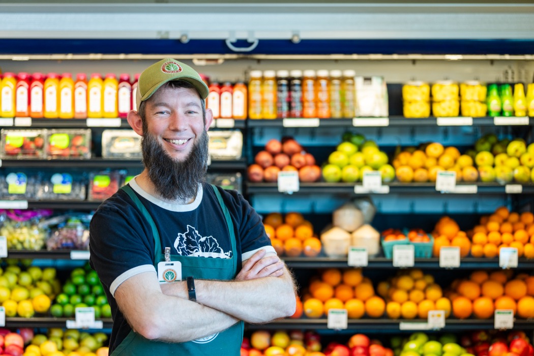 Friendly City Food Co-op employee posing in front of produce aisle