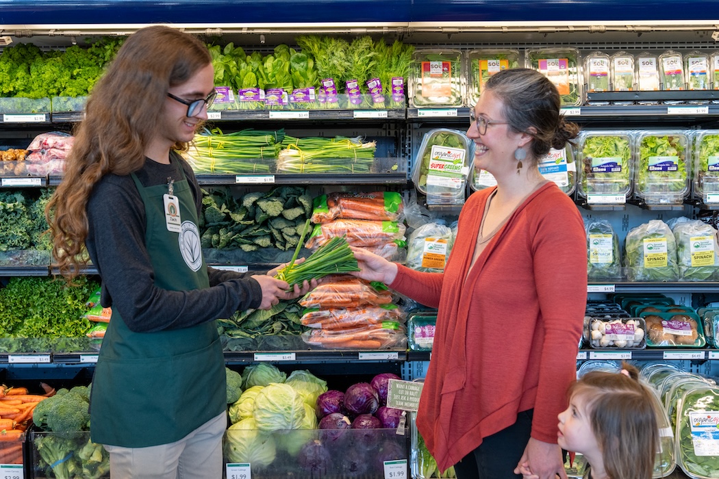 Friendly City Food Co-op employee helping customer in the vegetable aisle